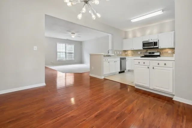 a kitchen with stainless steel appliances granite countertop a stove top oven a sink dishwasher and a refrigerator with wooden floor