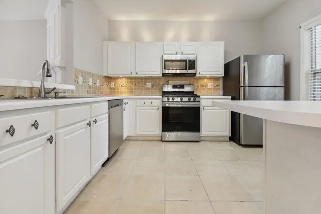 a kitchen with white cabinets and stainless steel appliances