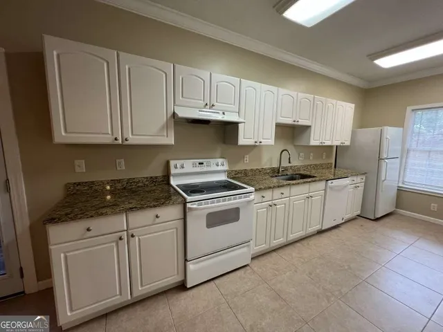 a kitchen with granite countertop white cabinets and white appliances