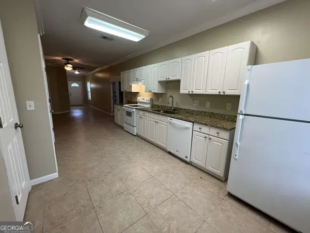 a kitchen with stainless steel appliances granite countertop a refrigerator a sink dishwasher a stove and white countertops with wooden floor