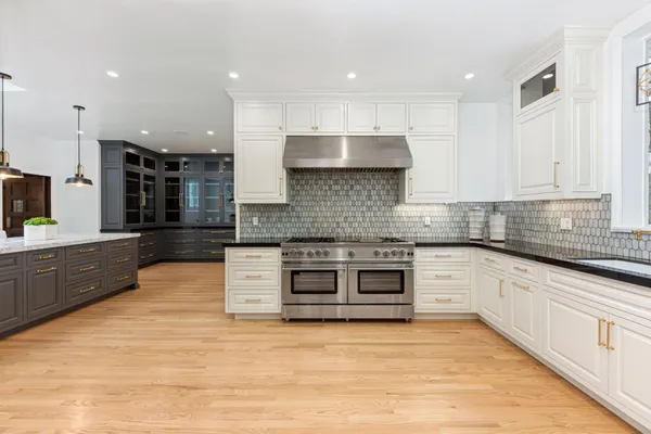 a large kitchen with stainless steel appliances a refrigerator a sink dishwasher a oven and a dining table with wooden floor