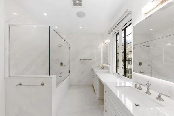 a large white bed sitting in a bedroom next to a large window