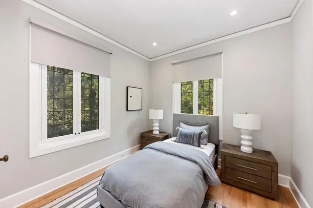 a large white bed sitting in a bedroom next to a large window