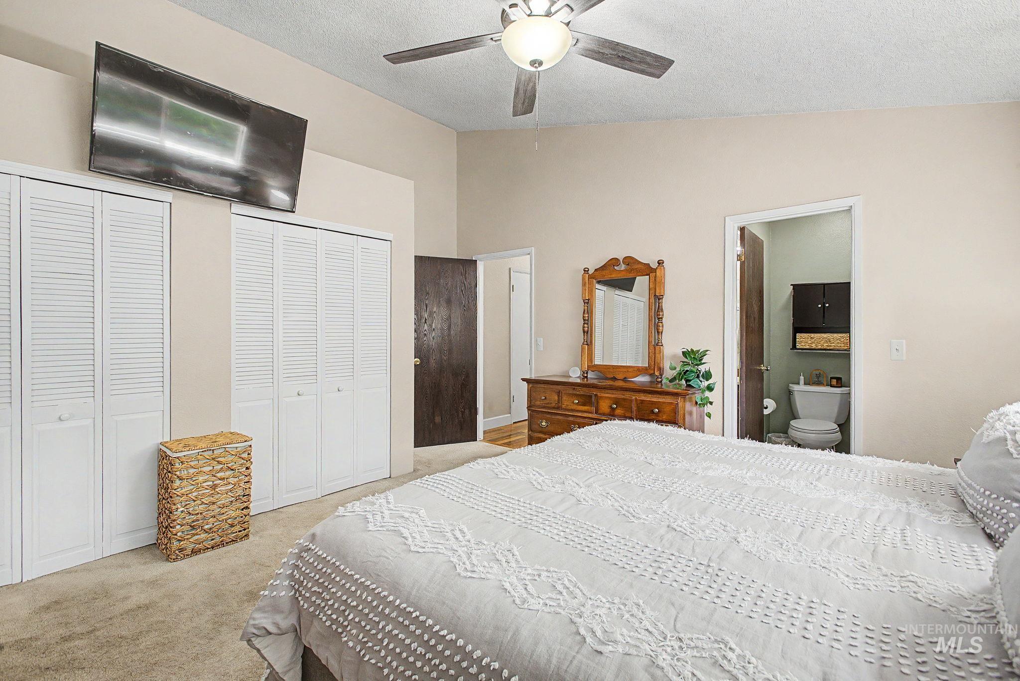 501 Karin Avenue Lewiston, ID 83501 - Photo 13 of 50 Bedroom featuring multiple closets, light colored carpet, a textured ceiling, ceiling fan, and connected bathroom