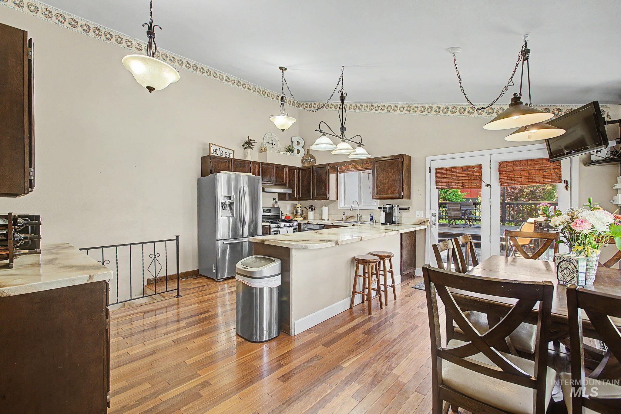 501 Karin Avenue Lewiston, ID 83501 - Photo 22 of 50 Kitchen with dark wood finish cabinets, stainless steel appliances, light wood-style floors, a breakfast bar area, and pendant lighting