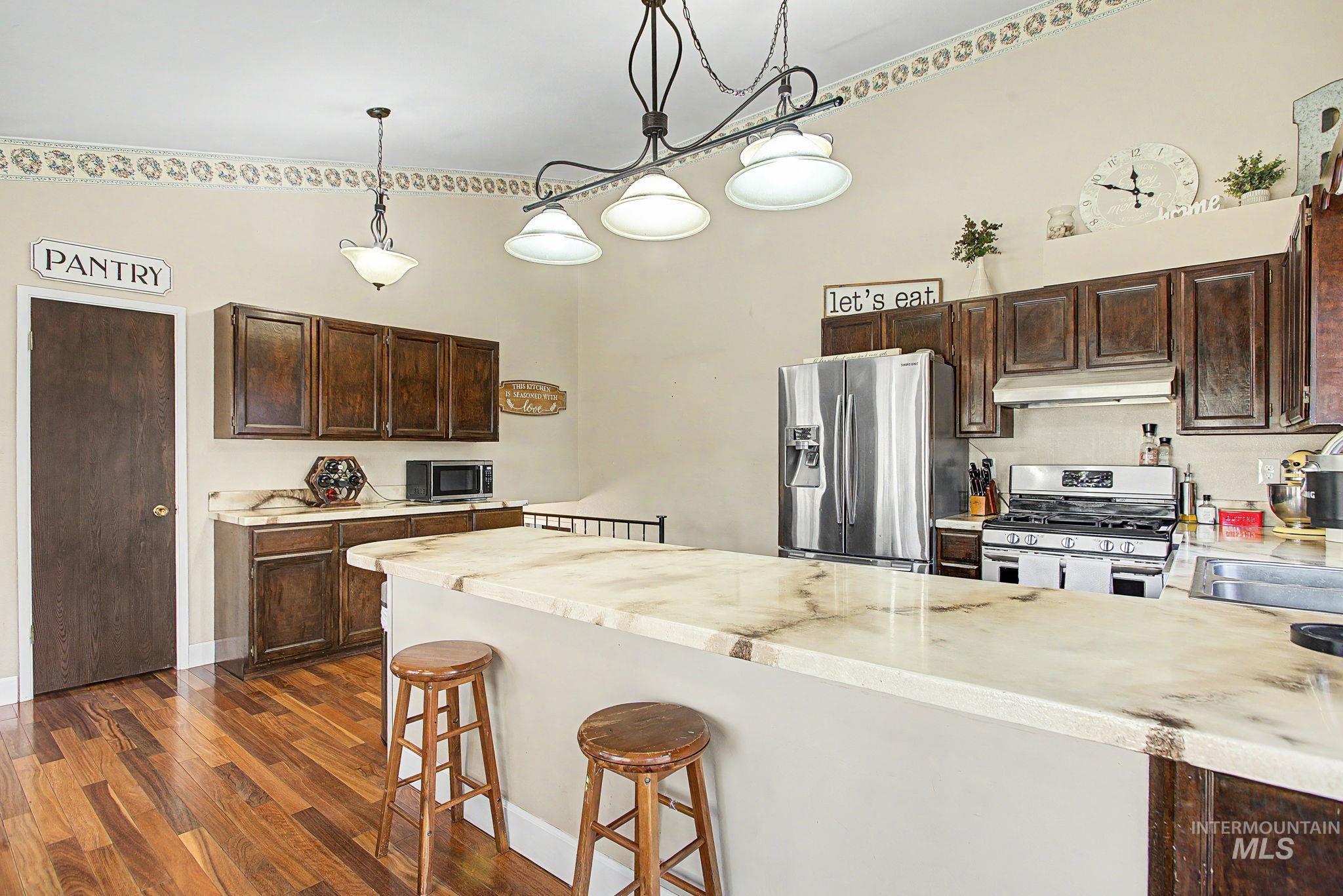 501 Karin Avenue Lewiston, ID 83501 - Photo 24 of 50 Kitchen with dark wood finish cabinets, a kitchen breakfast bar, stainless steel appliances, a peninsula, and dark wood finished floors