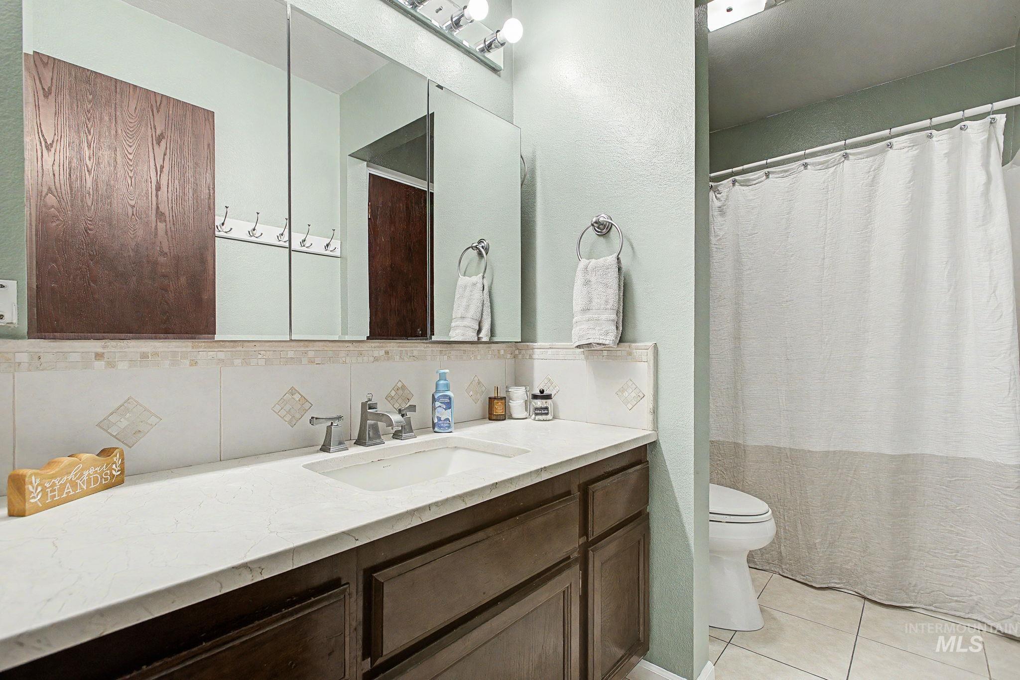 501 Karin Avenue Lewiston, ID 83501 - Photo 30 of 50 Bathroom featuring vanity, light tile patterned floors, curtained shower, and tasteful backsplash