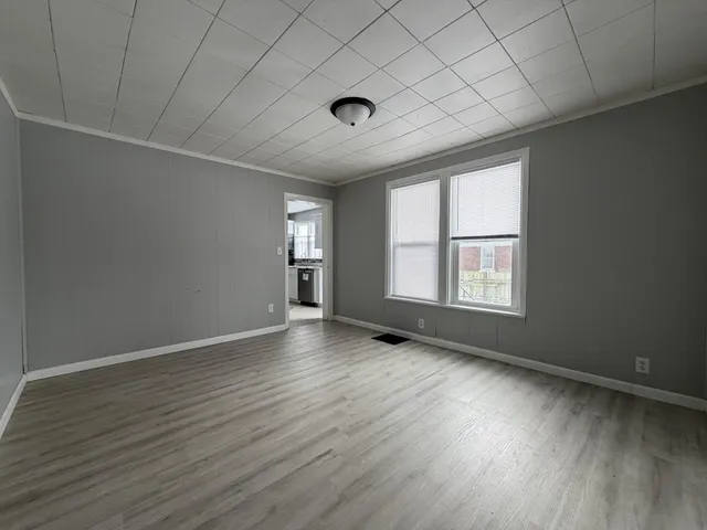 a view of hallway with window and wooden floor