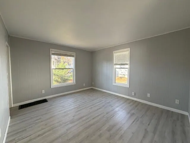 an empty room with wooden floor and window