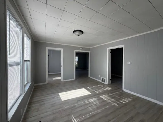 an empty room with wooden floor and windows
