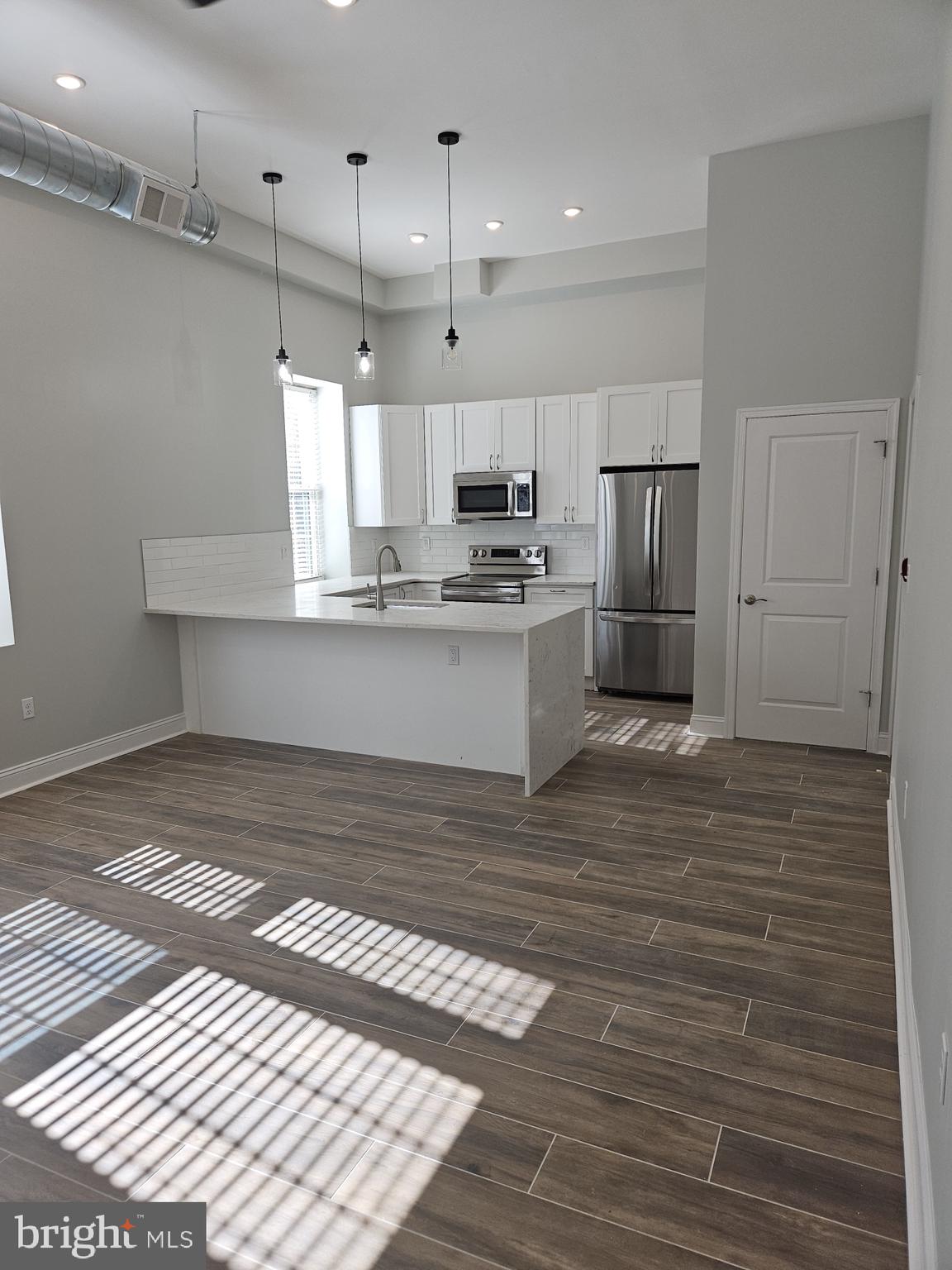 a view of kitchen and empty room with wooden floor