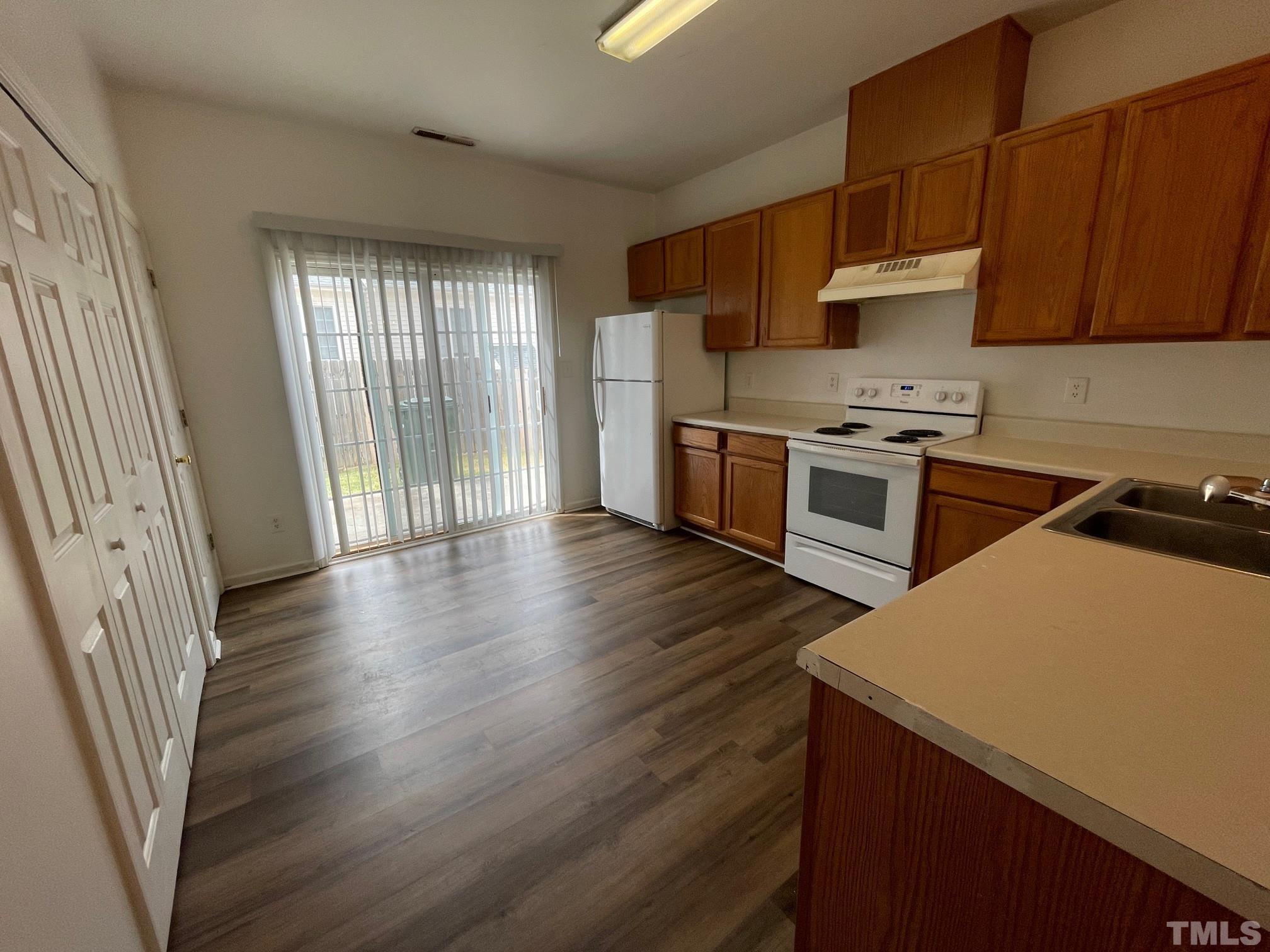 4631 Ravi Road Raleigh, NC 27604 - Photo 7 of 18 a kitchen with stainless steel appliances a stove a sink a refrigerator wooden floor and cabinets