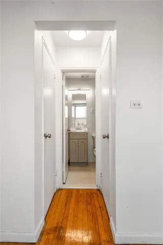 a view of a hallway with wooden floor and a bathroom