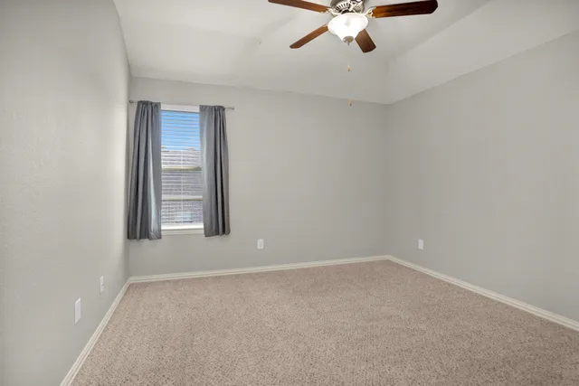 a view of an empty room with a ceiling fan and a window