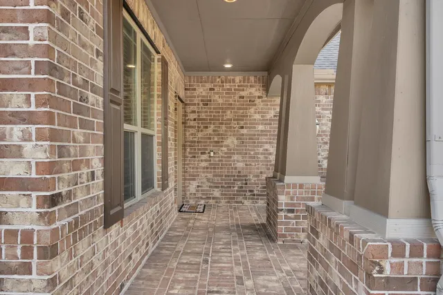 a view of a hallway with wooden floor and a bathroom