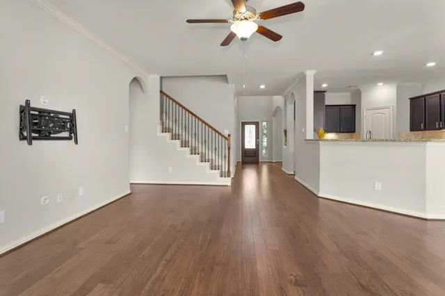 a view of an empty room with wooden floor and a kitchen