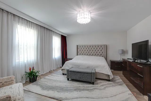 a bedroom with a large bed and a flat tv screen on a dresser