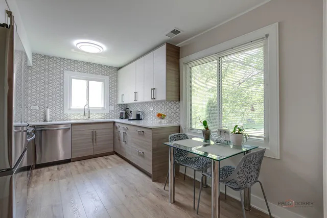 a kitchen with a stove a sink and white cabinets with wooden floors