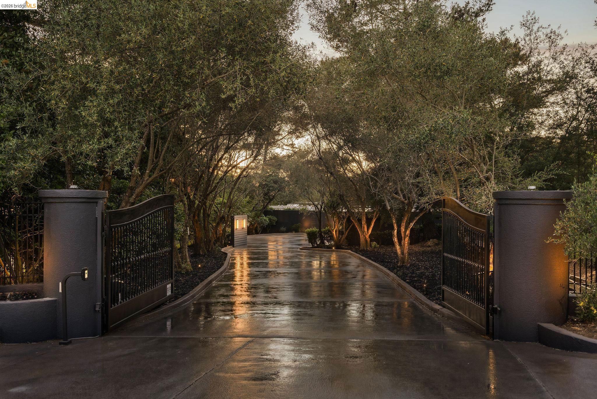 5645 Bacon Road Oakland, CA 94619 - Photo 5 of 94 Gated entry featuring wrought iron gates, stucco pillars, and a paved driveway