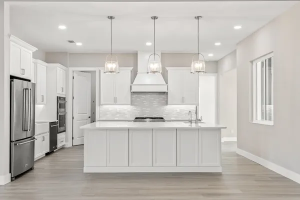 a kitchen with stainless steel appliances a sink a stove a refrigerator cabinets and chairs