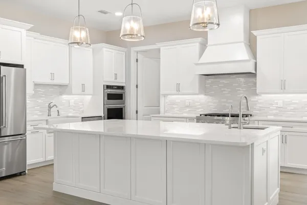 a large kitchen with white cabinets and stainless steel appliances