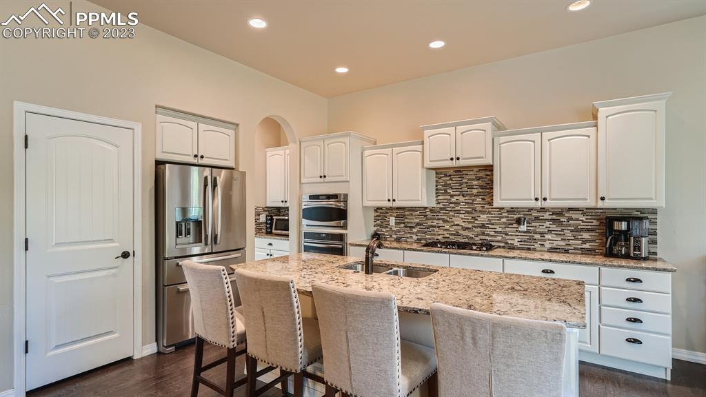 1118 Spectrum Loop Colorado Springs, CO 80921 - Photo 6 of 30 a kitchen with stainless steel appliances kitchen island granite countertop a refrigerator and cabinets