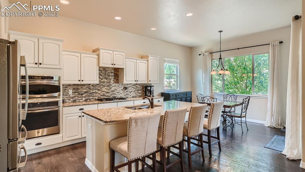 1118 Spectrum Loop Colorado Springs, CO 80921 - Photo 8 of 30 a kitchen with stainless steel appliances granite countertop a stove a refrigerator a kitchen island a table and chairs
