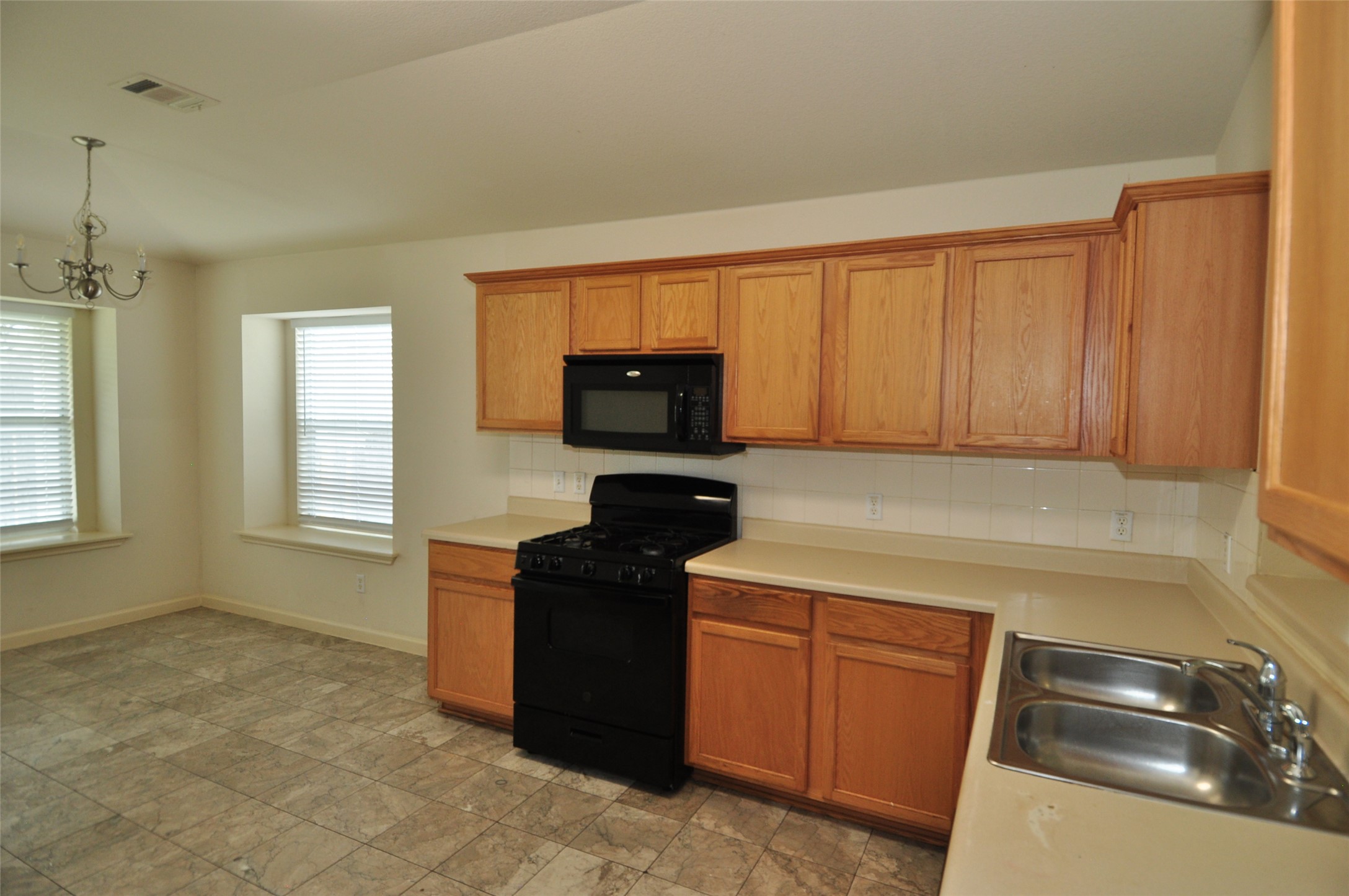 1409 Tea Leaf Drive Pflugerville, TX 78660 - Photo 5 of 18 A well-lit kitchen with natural wood cabinetry and resilient tile flooring invites culinary creativity.