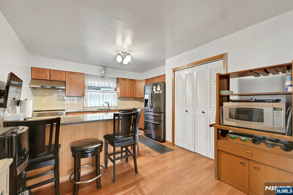 68 Bergen Turnpike Ridgefield Park, NJ 07660 - Photo 10 of 35 a kitchen with stainless steel appliances a stove a sink dishwasher a refrigerator cabinets and a dining table with wooden floor