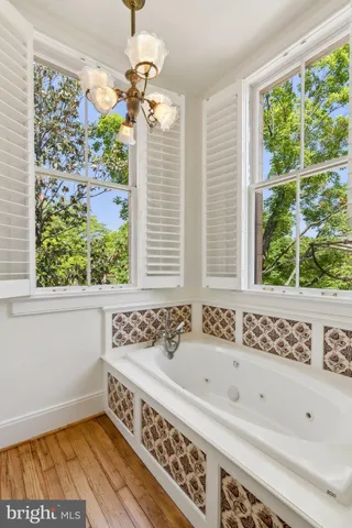 a view of an empty room with wooden floor fireplace and a window