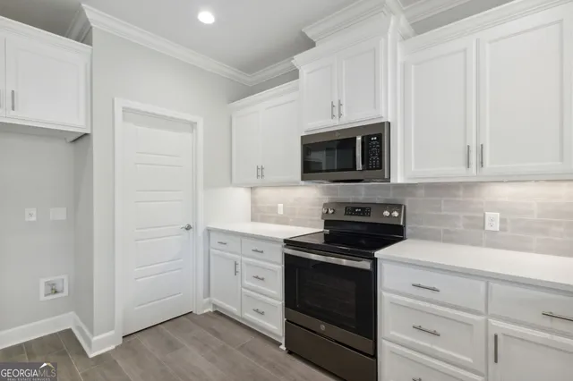 a kitchen with white cabinets and stainless steel appliances