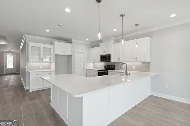 a large white kitchen with kitchen island a sink a center island stainless steel appliances and a living room view