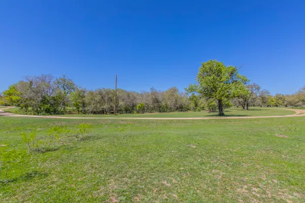 a view of a green field with trees in the background