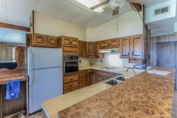 a kitchen with stainless steel appliances granite countertop a refrigerator a stove and a sink with wooden cabinets