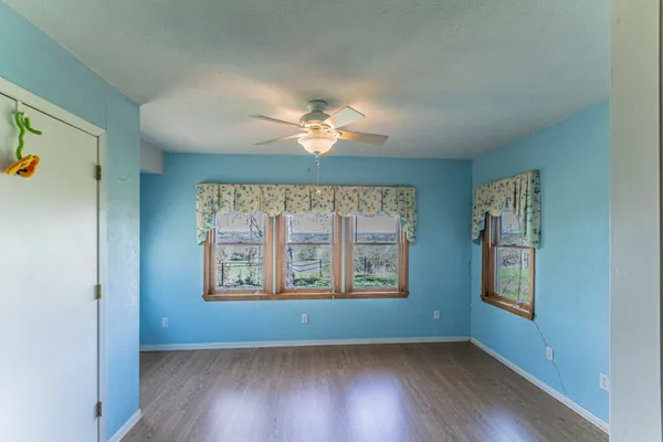 an empty room with windows and chandelier fan