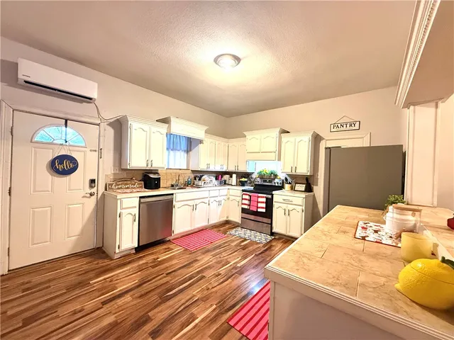 a kitchen with a refrigerator and wooden floor