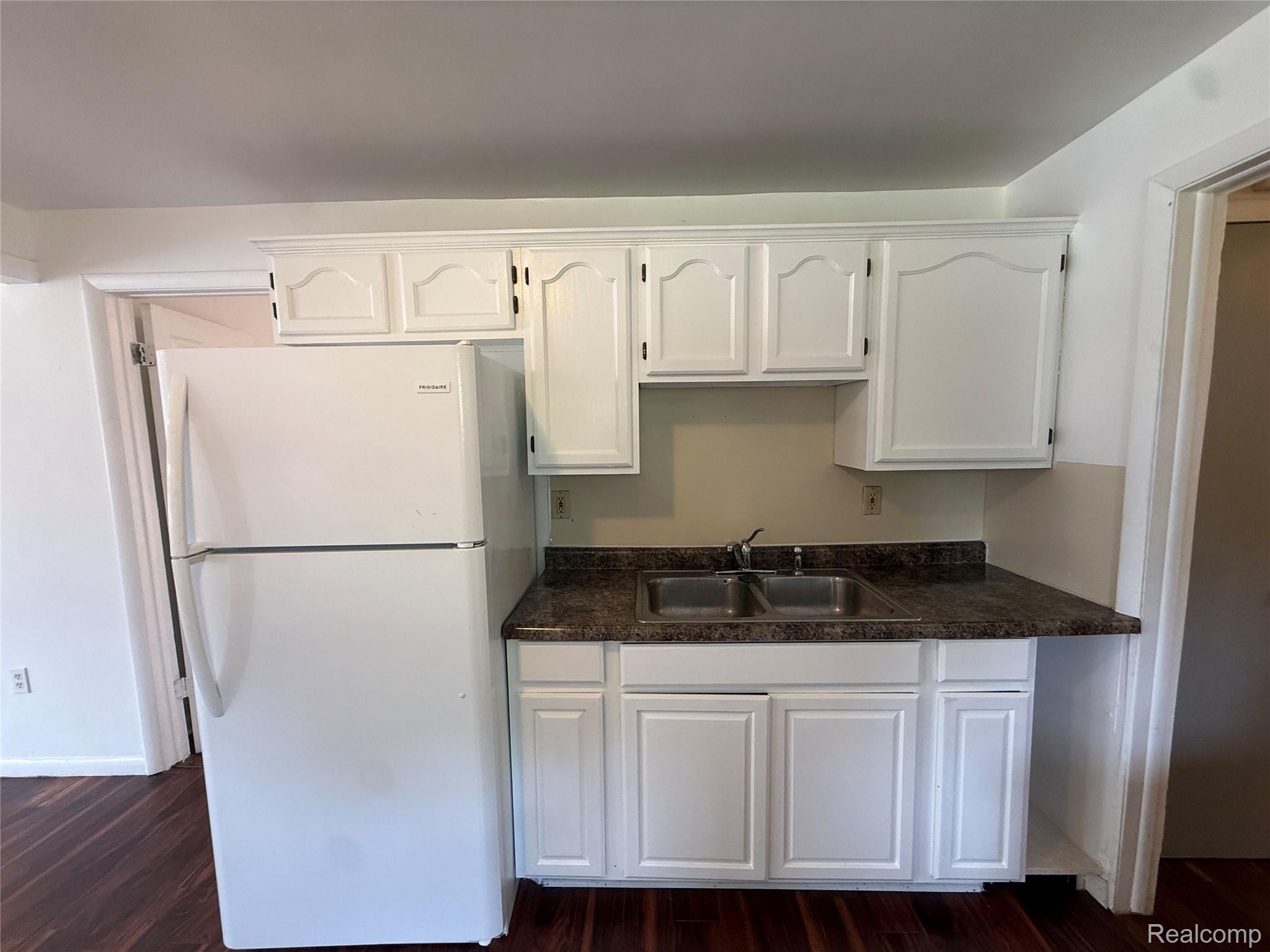 2194 East Bristol Road Burton, MI 48529 - Photo 6 of 13 Kitchenette featuring white cabinetry, a double basin stainless steel sink, a dark speckled countertop, and wood-finish flooring