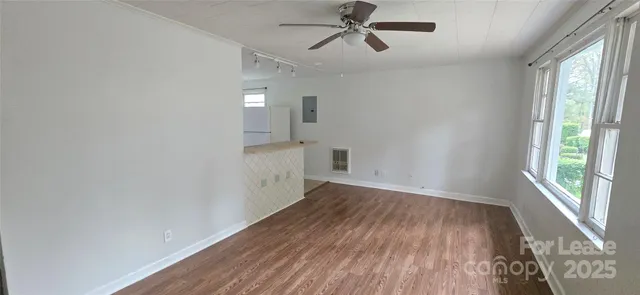 a view of empty room with wooden floor and fan