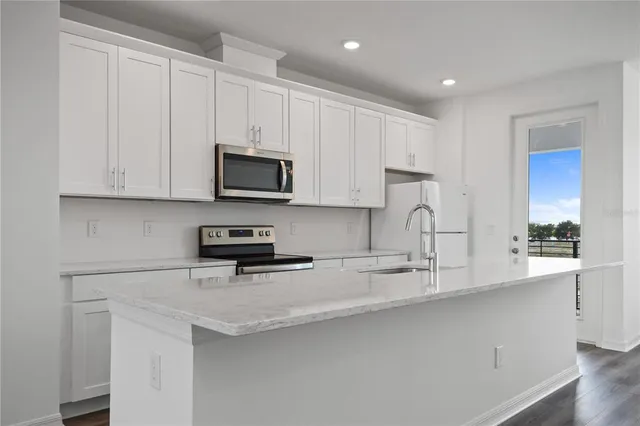 a kitchen with stainless steel appliances granite countertop a sink a stove and microwave with wooden floor