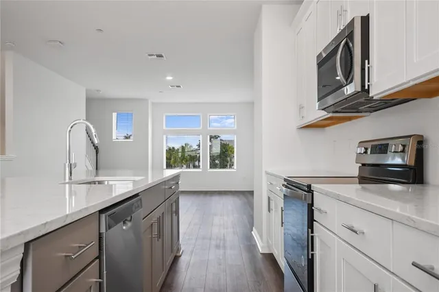 a kitchen with stainless steel appliances granite countertop a sink a stove and a microwave oven with cabinets