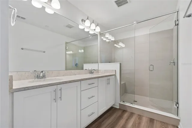 a bathroom with a double vanity sink mirror and shower