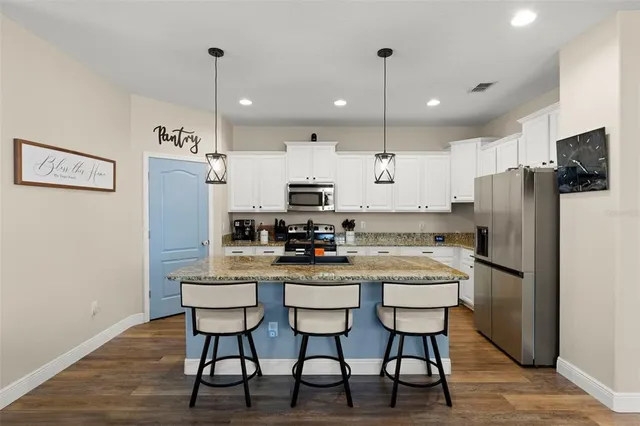 a kitchen with stainless steel appliances granite countertop a dining table chairs refrigerator and microwave