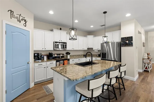 a kitchen with stainless steel appliances granite countertop a kitchen island a stove a refrigerator a oven a sink with a dining table and chairs