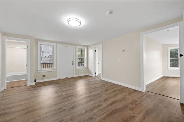 a view of an empty room with window and wooden floor