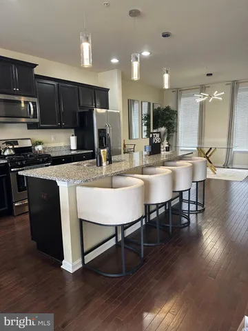 a kitchen with stainless steel appliances granite countertop a stove top oven a sink dishwasher a dining table and chairs with wooden floor