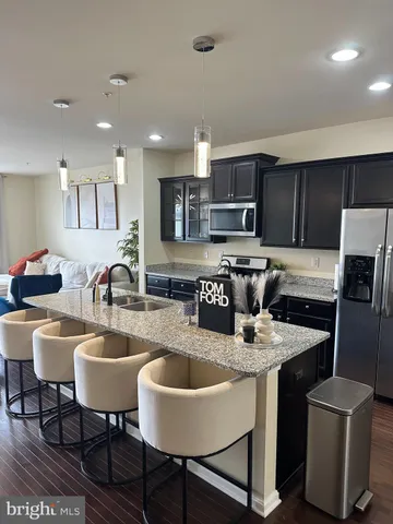 a kitchen with stainless steel appliances granite countertop a table chairs sink refrigerator and microwave