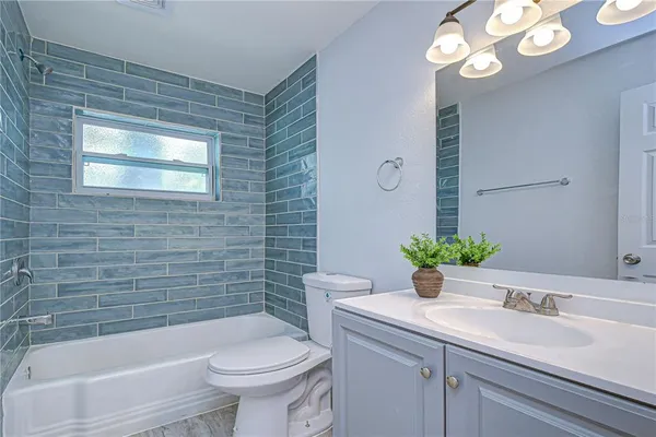 a bathroom with a sink a toilet a mirror and shower