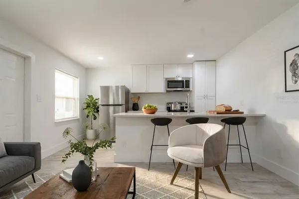 a living room with furniture kitchen and a potted plant