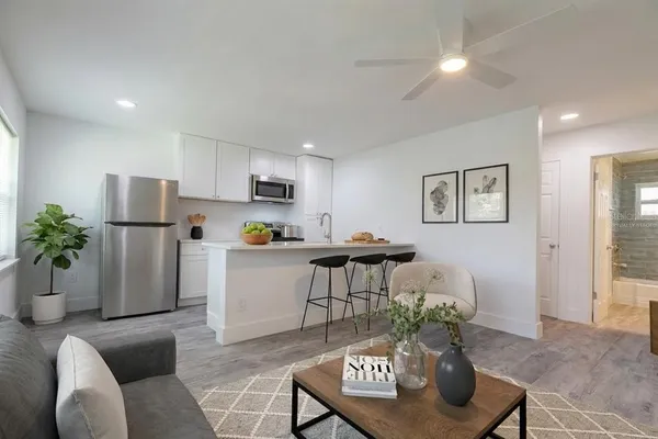 a living room with furniture a refrigerator and a potted plant