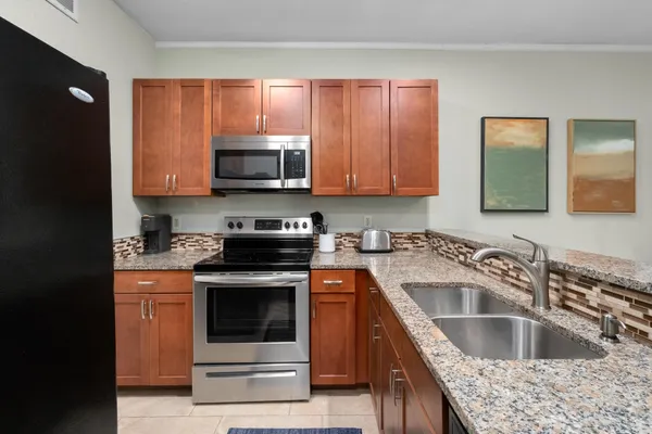 a kitchen with granite countertop a sink stove and microwave